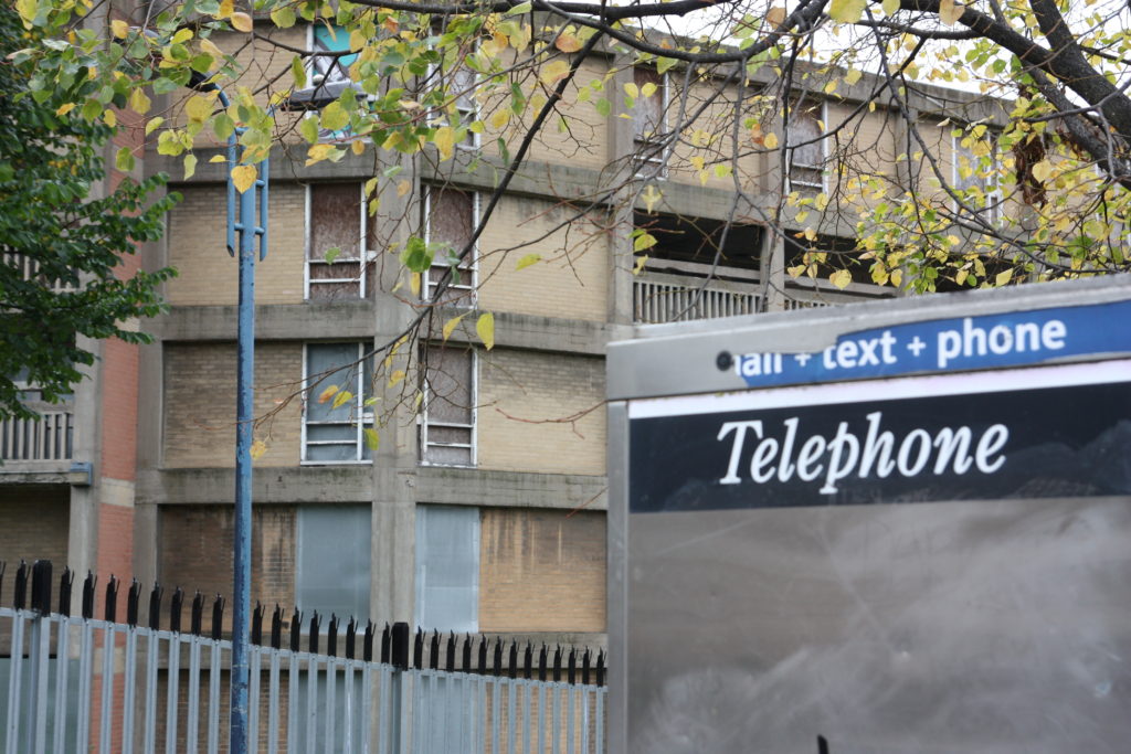 Decrepit phone box in front of concrete flats at Park Hill